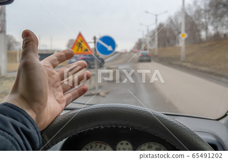 the hand of a car driver who is outraged by road repairs 65491202