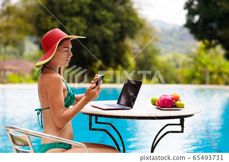 Woman with laptop at swimming pool. Remote work. 65493731
