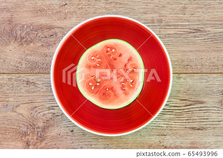 small ripe halved watermelon on a red plate on a small ripe halved watermelon on a red plate on a 65493996