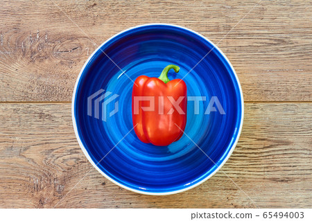 red bell pepper on a blue plate on a wooden 65494003