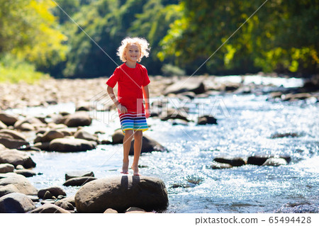 Child hiking in mountains. Kids at river shore. Child hiking in mountains. Kids at river shore. 65494428