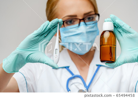 medical doctor nurse woman wearing protective mask and rubber or latex gloves - holding can of medicine and thermometer 65494458