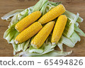 peeled yellow corn on a background of green leaves on a wooden table 65494826