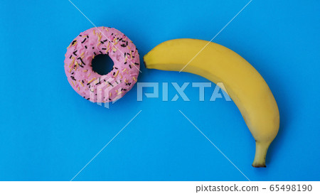 Sweet donut and banana on blue color background. Erotic concept 65498190