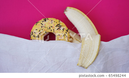 Sweet donut and banana on pink color background. Erotic concept 65498244