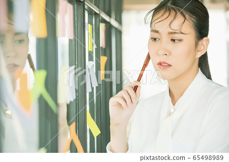 Young pretty woman office worker smile sticky note window sticking memo pen person material 65498989