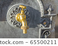 brass water tap on stone wall background, blurred background 65500211