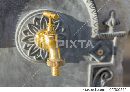 brass water tap on stone wall background, blurred background brass water tap on stone wall background, blurred background 65500211