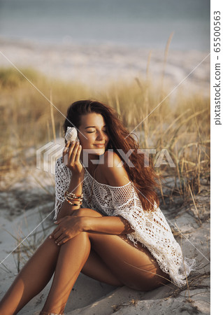 Woman With Seashell on the Beach During Vacations Woman With Seashell on the Beach During Vacations 65500563