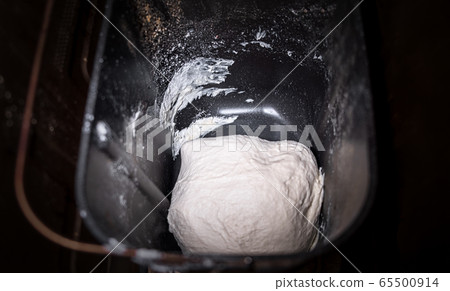 Dough in bread pan of autimatic breadmaker for home use. Not raised dough preparing for baking in smart bread maker machine loaf-pan. Dough in bread pan of autimatic breadmaker for home use. Not raised dough preparing for baking in smart bread maker machine loaf-pan. 65500914