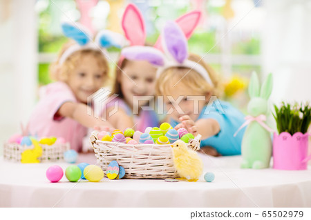 Kids on Easter egg hunt. Children dye eggs. 65502979