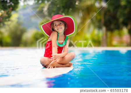Child with hat in swimming pool. Tropical vacation 65503178