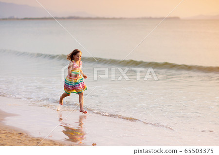 Child playing on ocean beach. Kid at sunset sea. 65503375