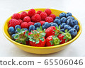small fruit raspberries strawberries and blueberries close up in a yellow plate 65506046