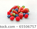 small fruits raspberries strawberries and blueberries close-up on a light background 65506757