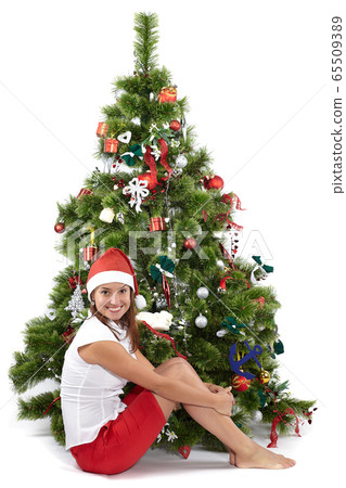 Beautiful smiling woman in Santa cap, sitting near 65509389