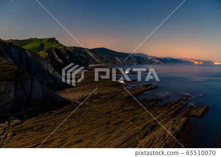 Night view of flysch and shellfishermen with low tide and full moonlight in Zumaia 65510070