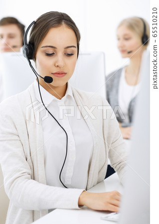 Call center. Group of diverse operators at work. Beautiful woman in headset communicating with customers of telemarketing service. Business concept Call center. Group of diverse operators at work. Beautiful woman in headset communicating with customers of telemarketing service. Business concept 65510210