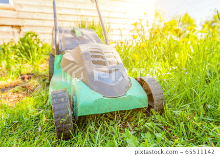 Lawn mower cutting green grass in backyard Lawn mower cutting green grass in backyard 65511142
