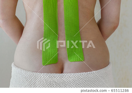 Special therapeutic tape on the back of a woman, muscle recovery, kinesiology tape Special therapeutic tape on the back of a woman, muscle recovery, kinesiology tape 65511286