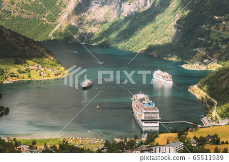 Geirangerfjord, Norway. Aerial View Of Geiranger In Geirangerfjorden In Summer Day. Touristic Ship Ferry Boat Liner Moored Near Geiranger. Famous Norwegian Landmark And Popular Destination Geirangerfjord, Norway. Aerial View Of Geiranger In Geirangerfjorden In Summer Day. Touristic Ship Ferry Boat Liner Moored Near Geiranger. Famous Norwegian Landmark And Popular Destination 65511989