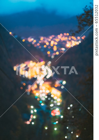 Borjomi, Samtskhe-Javakheti, Georgia. Abstract Blurred Bokeh Boke Background Of Evening Borjomi Cityscape And Central Park In Night Illuminations Lighting 65512032