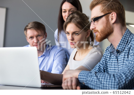 Serious team leader explaining online data on laptop to colleagu 65512042