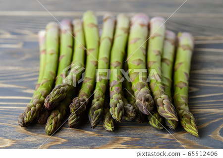 Bunch of fresh raw green asparagus stalks on a dark wood table.  65512406