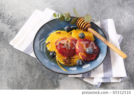 Citrus dessert. Orange carpaccio from yellow and blood oranges with honey, spices and blueberries 65512510