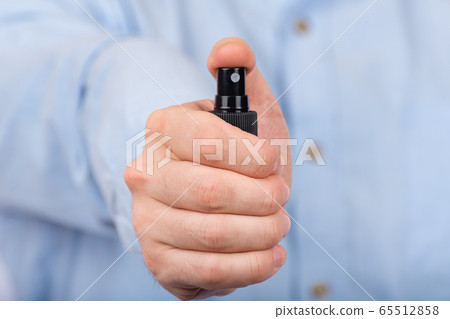 Man's hand holds protective antibacterial spray. 65512858