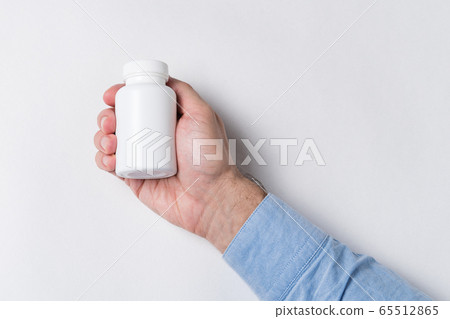 Hand holding white jar of pills. Pharmaceutical Hand holding white jar of pills. Pharmaceutical 65512865