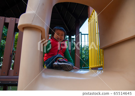 3 year old boy playing on a slide 65514645