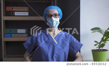 Tired doctor looks at camera wearing protective medical uniform, mask, cap and glasses. Female nurse feeling stress due to overwork during a pandemic Tired doctor looks at camera wearing protective medical uniform, mask, cap and glasses. Female nurse feeling stress due to overwork during a pandemic 65516312