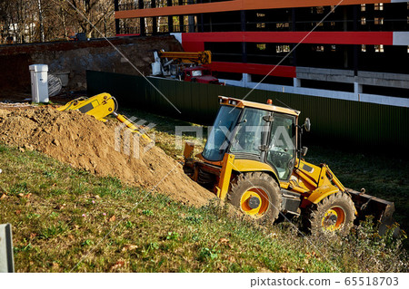 Yellow loader backhoe digs under the road Yellow loader backhoe digs under the road 65518703