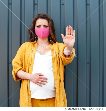 Pregnant woman in a protective mask and yellow 65520341