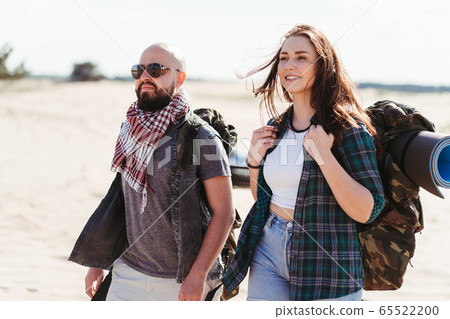 Tourists with backpacks traveling through desert Tourists with backpacks traveling through desert 65522200