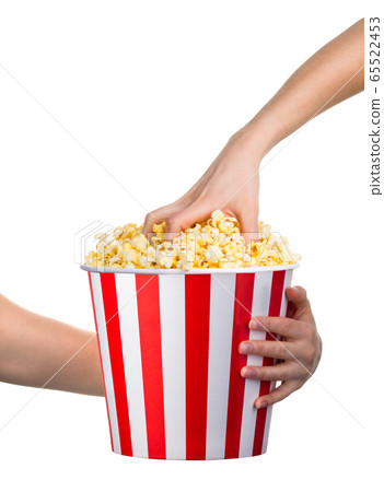 Woman hand taking popcorn from striped bucket Woman hand taking popcorn from striped bucket 65522453