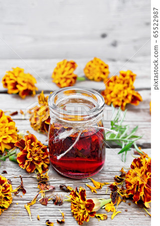 Alcohol tincture of marigolds in jar on old wooden 65522987