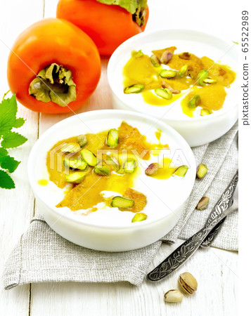 Dessert of yogurt and persimmon two bowls on light Dessert of yogurt and persimmon two bowls on light 65522989