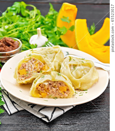 Manty with meat and pumpkin in plate on black 65523017