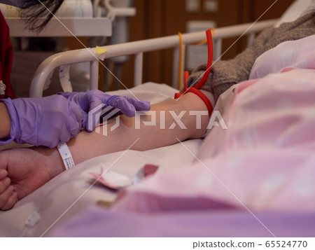 A nurse inserting a canula into a patient's arm A nurse inserting a canula into a patient's arm 65524770