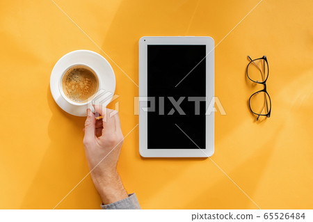 Man's hand with cup of coffee, tablet with blank screen and glasses on yellow background, Man's hand with cup of coffee, tablet with blank screen and glasses on yellow background, 65526484