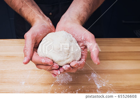 Close-up shot of man's hands holding homemade dough Close-up shot of man's hands holding homemade dough 65526608