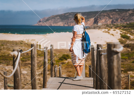 Adult female tourist enjoying costal view of Praia do Guincho Beach. Cascais, Portugal 65527152