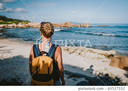 La Digue Island, Seychelles. Adult women with backpack enjoying beautiful tropical secluded beach in evening light 65527332