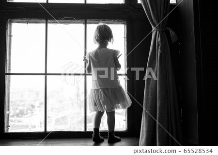 Child is standing and looking out the window. Stay at home and quarantine concept. Sadness of the toddler. Child is standing and looking out the window. Stay at home and quarantine concept. Sadness of the toddler. 65528534