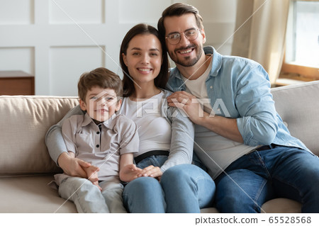 Portrait of happy young family relaxing on sofa together Portrait of happy young family relaxing on sofa together 65528568