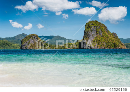 El Nido, Philippines. Crystal clear blue water lagoon and private Malapacao island in background El Nido, Philippines. Crystal clear blue water lagoon and private Malapacao island in background 65529166