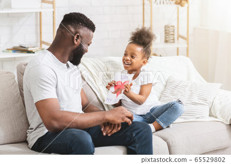 Sweet little black girl holding greeting card for her dad Sweet little black girl holding greeting card for her dad 65529802