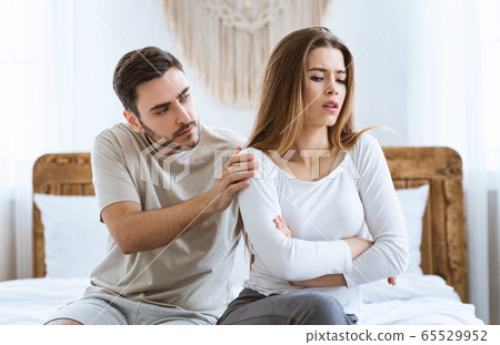 Man consoles an offended woman in interior at bedroom. Man consoles an offended woman in interior at bedroom. 65529952